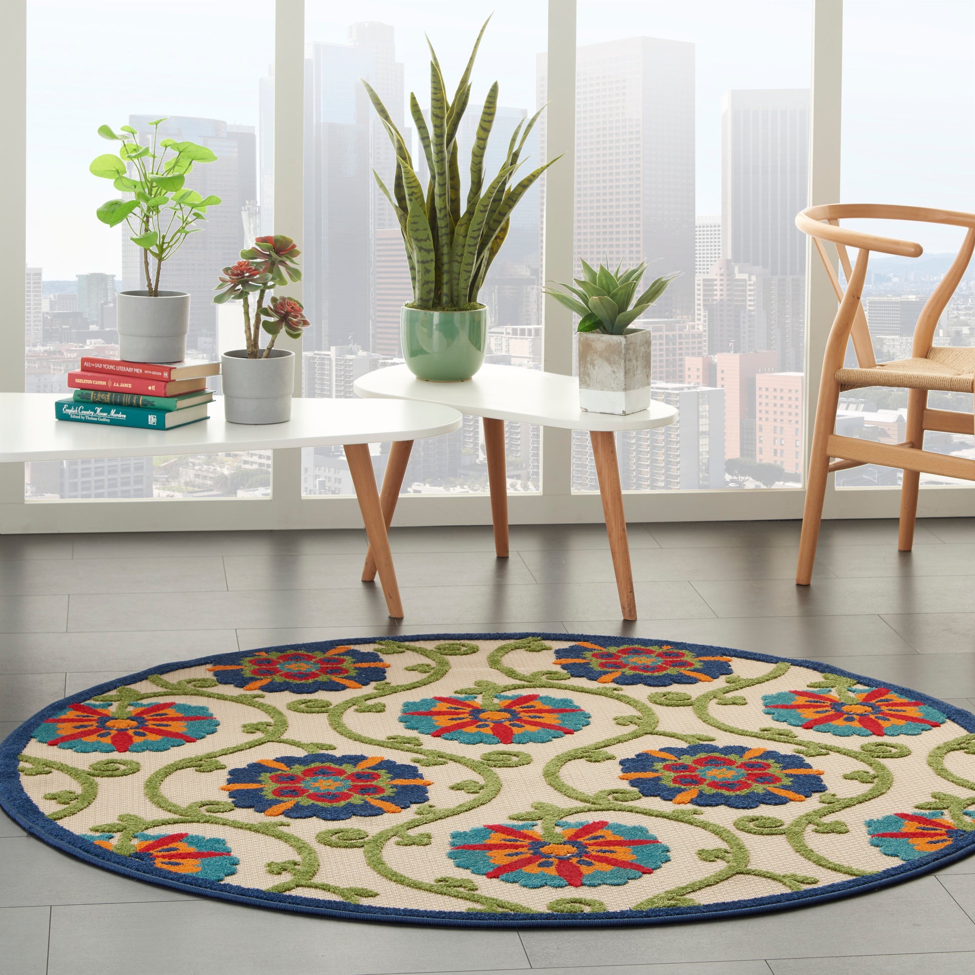 Round blue-bordered floral rug with green vines and red-blue flowers in a modern living room.