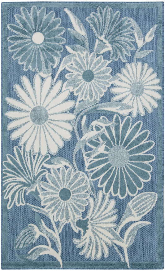 Rectangular blue outdoor area rug with large white daisies and pale blue leaves for a coastal botanical look.