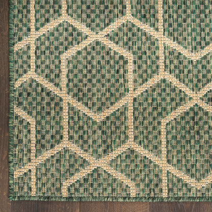 Teal-green woven rug with cream geometric diamonds and lattice pattern, fringe edging on dark wood floor.