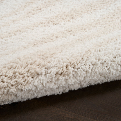 Cream shag rug with dense ivory-tinted plush pile on dark wood floor.