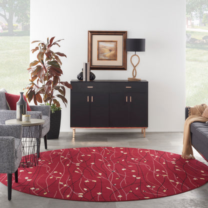 Round red rug with white leaf pattern under a black sideboard; framed art, rope lamp, gray seating and plant.