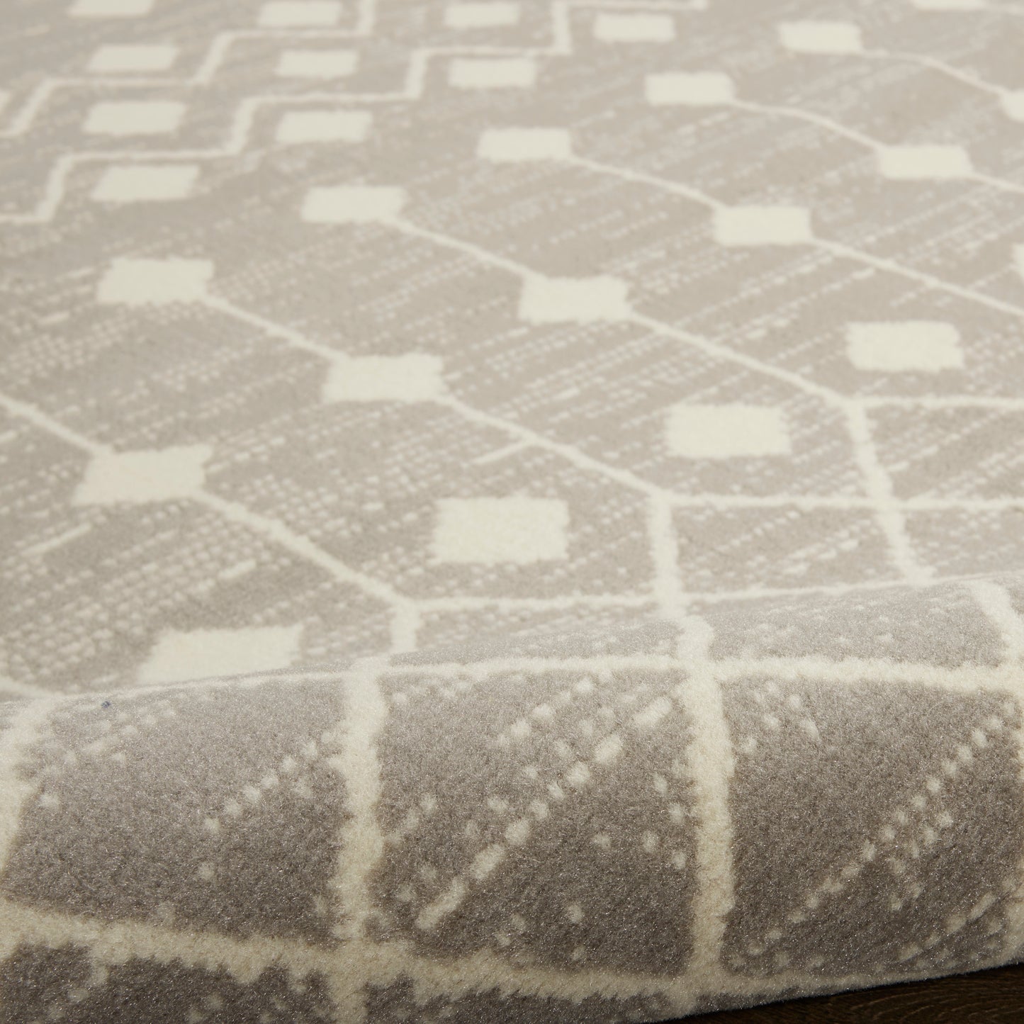 Close-up of a light gray woven rug with a white geometric lattice pattern of diamonds and squares, 4' x 6'.