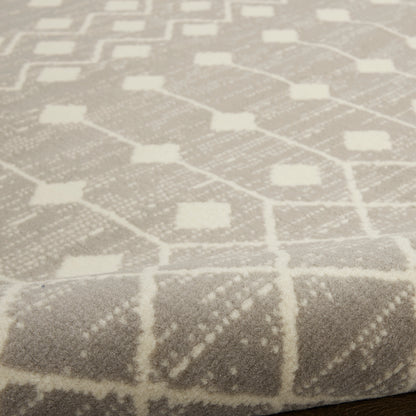 Close-up of a light gray woven rug with a white geometric lattice pattern of diamonds and squares, 4' x 6'.