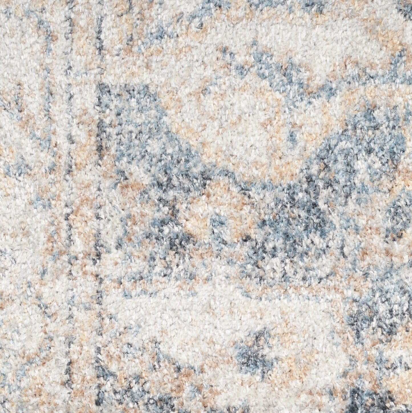 Close-up of a textured beige-blue-gray area rug with soft plush pile and abstract pattern.