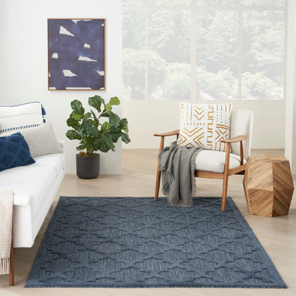 Cozy living room with white sofa, wooden armchair, blue rug, blue cushions, gray throw, potted plant, abstract blue wall art.