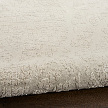 Cream textured area rug with embossed geometric pattern and soft pile, rolled edge on dark wood floor