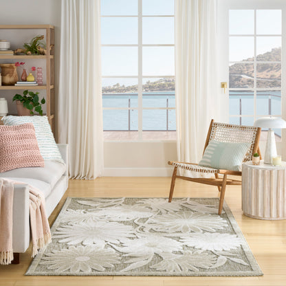 Bright coastal living room with large windows, beige sofa, pink and mint cushions, woven rug, wicker chair, sea view.