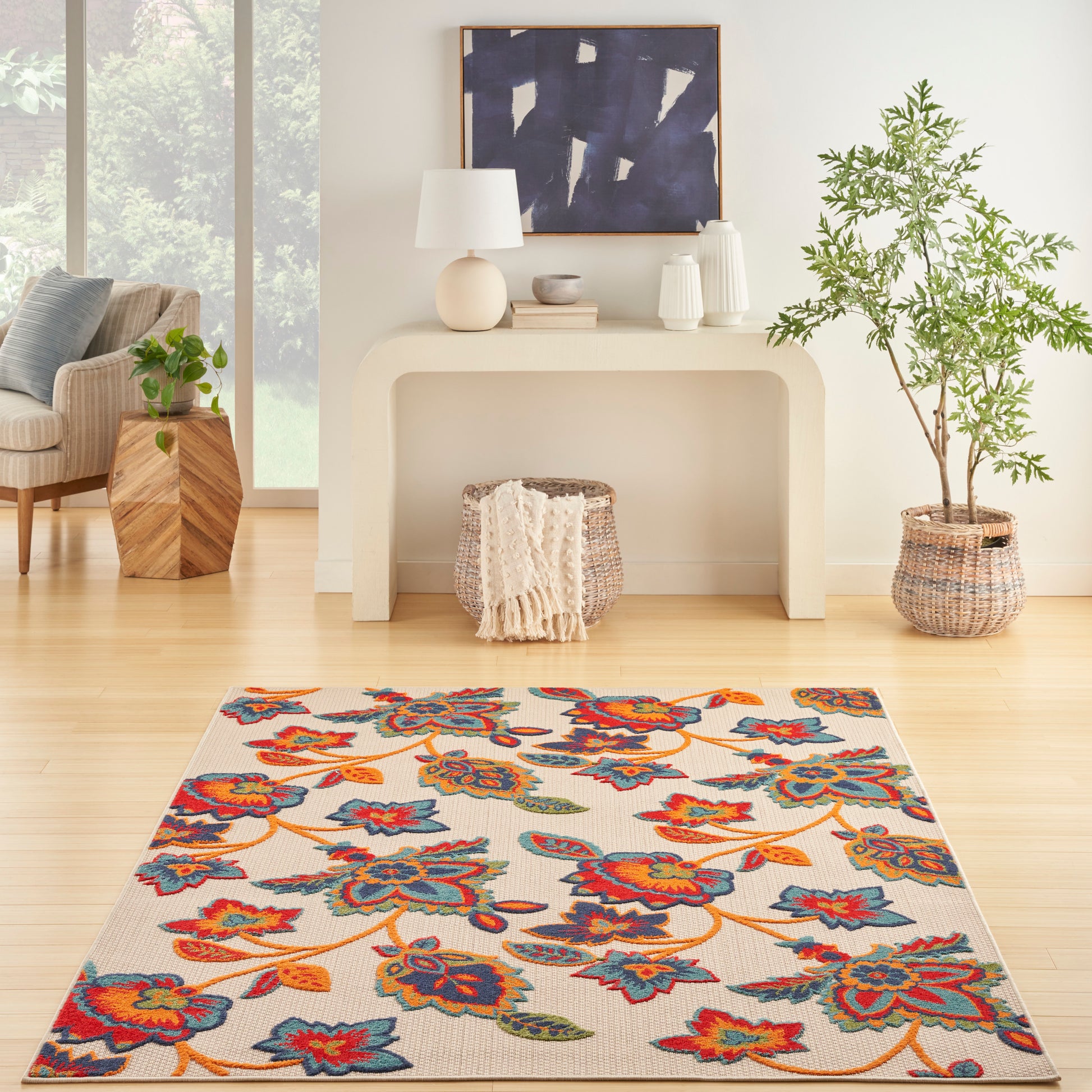 Vibrant floral area rug with red, orange, blue and teal flowers on beige in a bright modern living room.