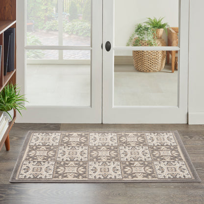 Rectangular entry rug with beige and grey tile-pattern squares, placed on wood floor by glass French doors.