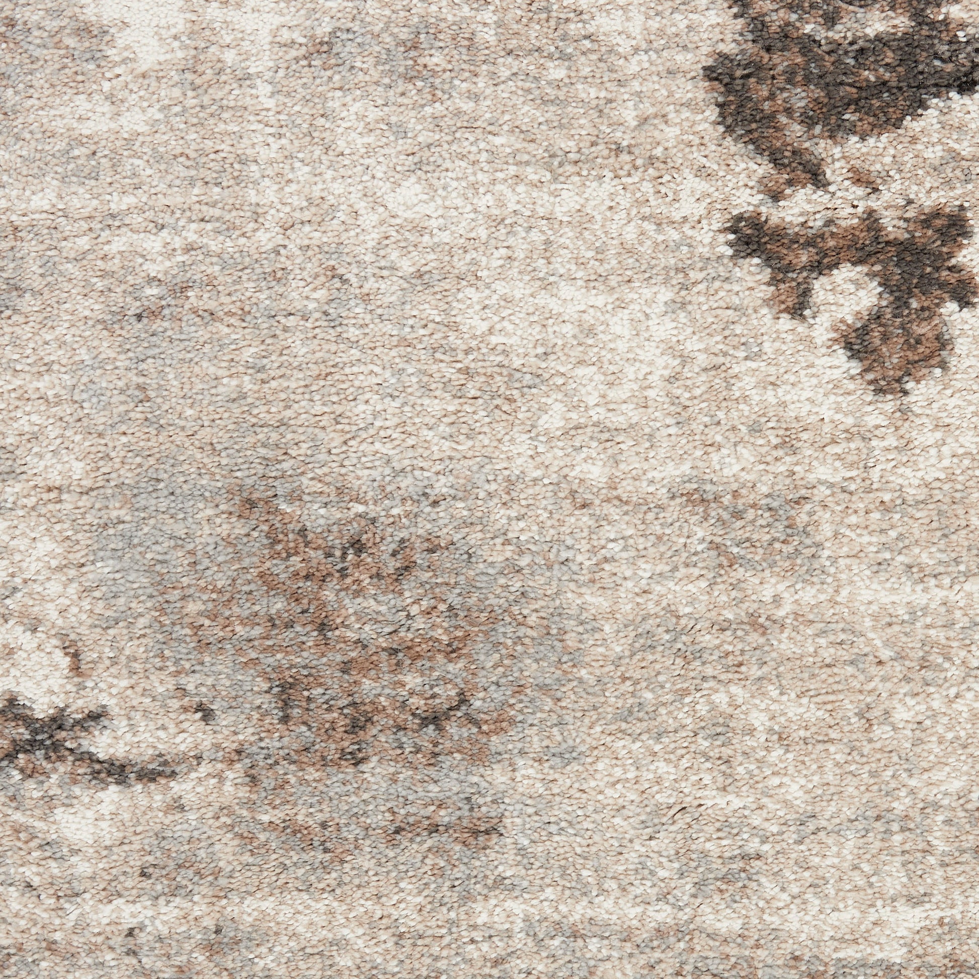 Neutral beige area rug with mottled texture and subtle dark brown floral accents.
