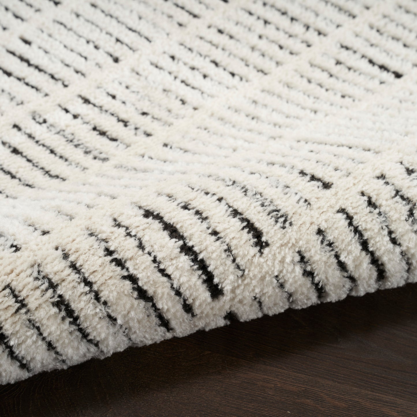 Cream shag rug with plush pile and black striped pattern; modern, cozy floor covering.
