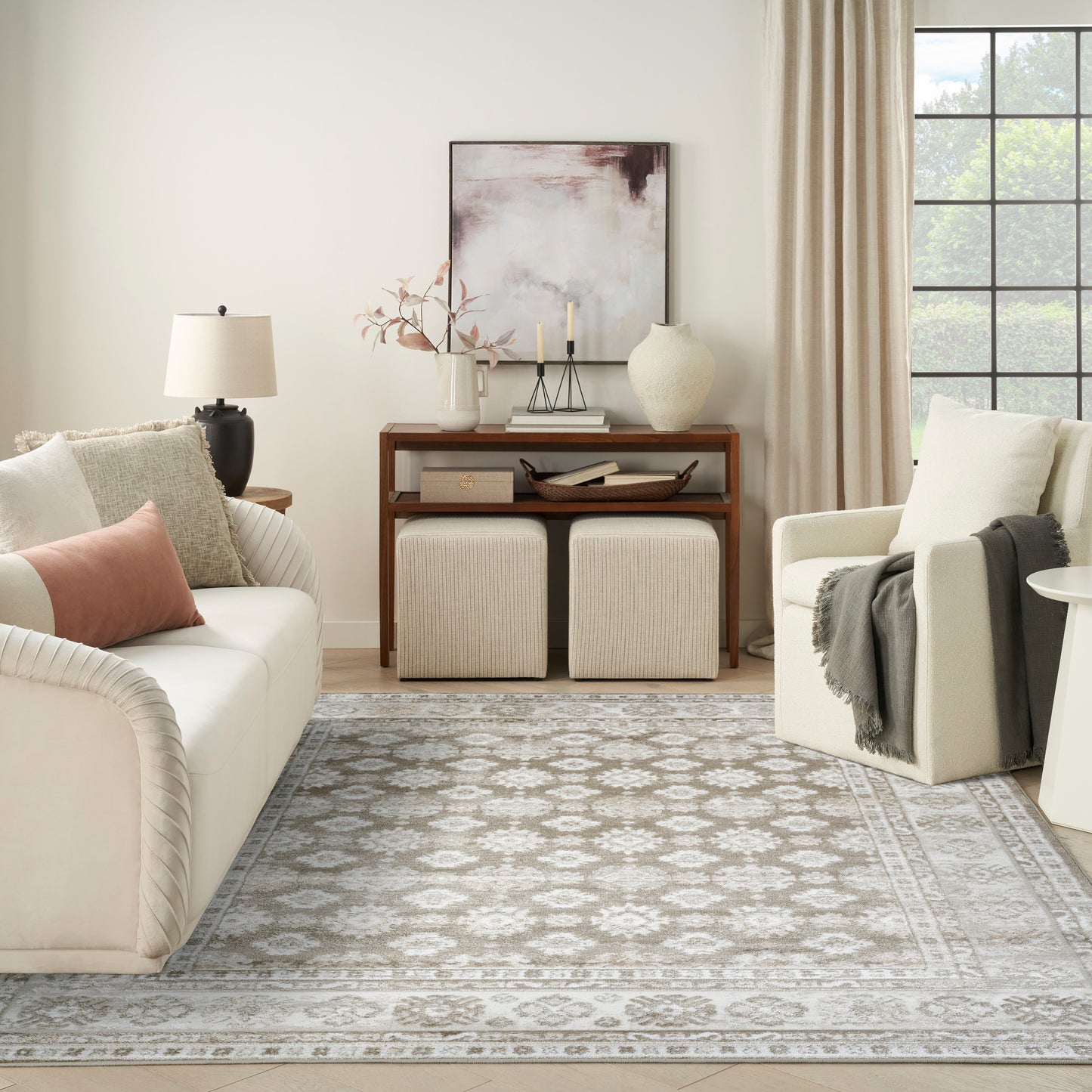 Neutral living room with cream sofa, beige cushions, gray patterned rug (8' x 10'), wooden console, two beige ottomans, armchair.