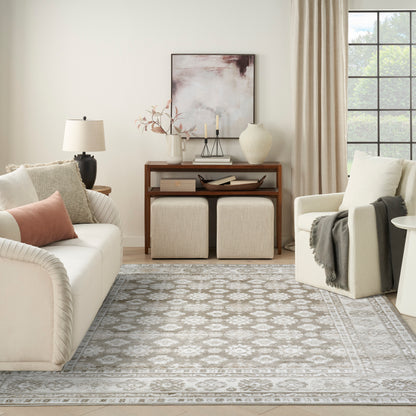 Neutral living room with cream sofa, beige cushions, gray patterned rug (8' x 10'), wooden console, two beige ottomans, armchair.