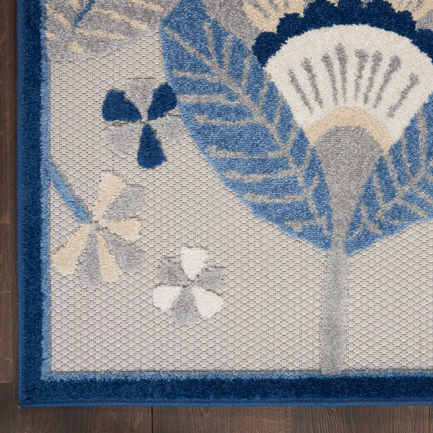 Woven rug with blue floral leaves on gray background and a navy border.