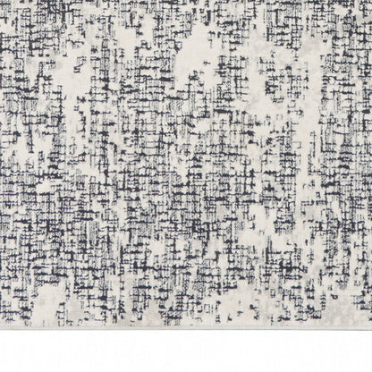 Close-up of a modern rug with ivory cream background and an irregular charcoal grid pattern along a woven texture.