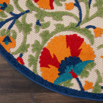 Round tufted floral area rug with vivid orange, red, teal petals, green vines on cream background and dark blue border.