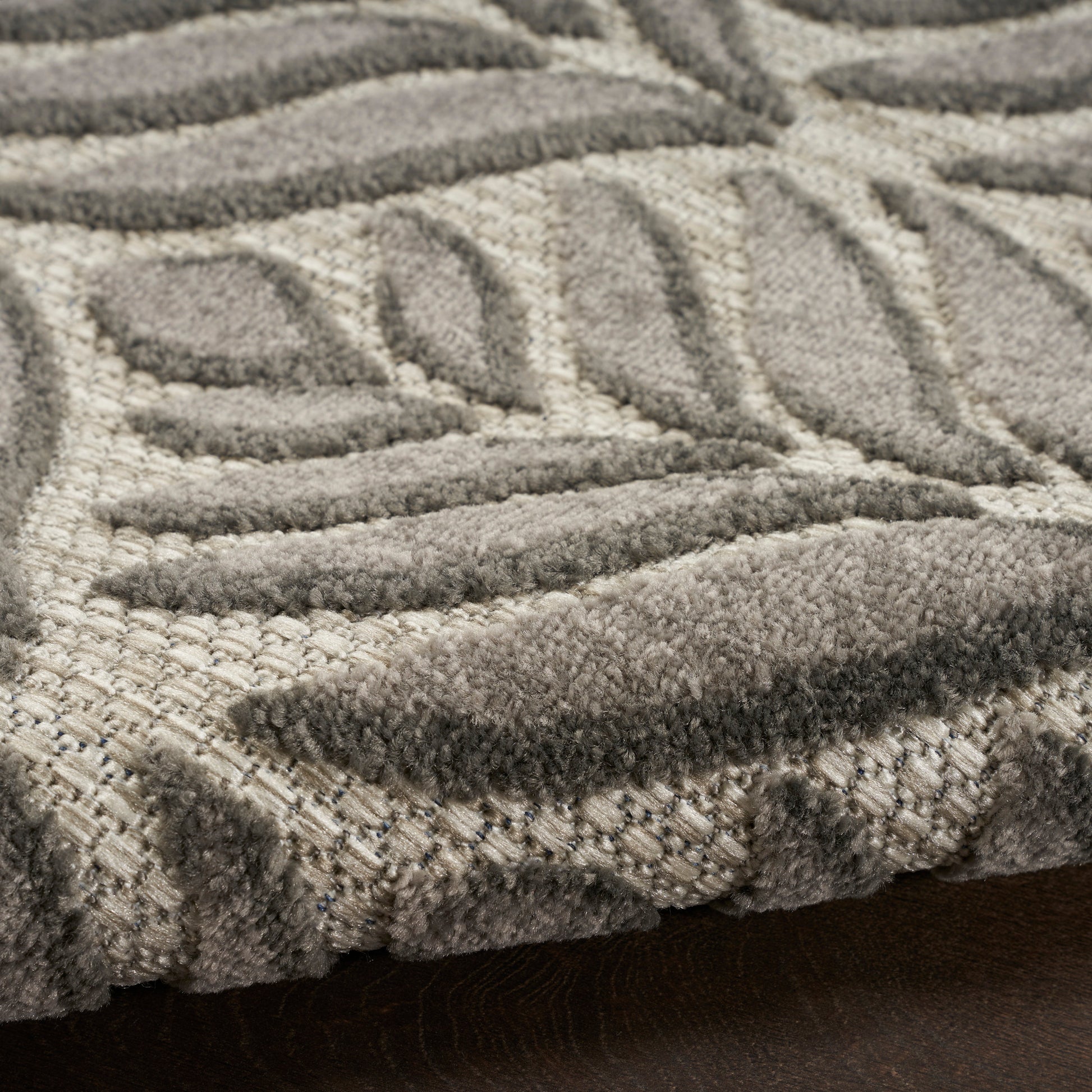 Close-up of a plush beige-gray rug with raised geometric leaf pattern and soft textured pile.