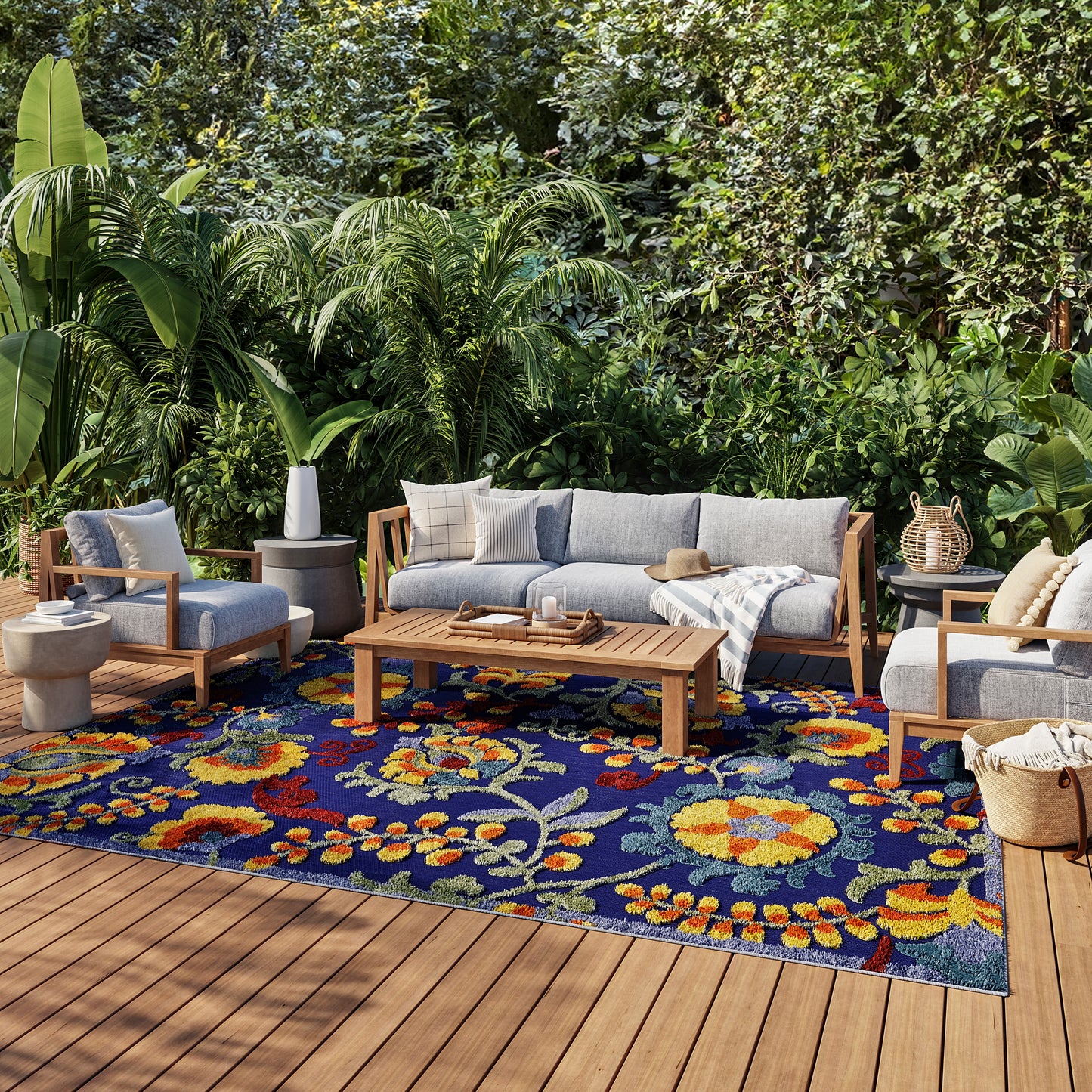 Outdoor rug 6' x 9' with a blue floral pattern on a wooden deck among tropical plants.