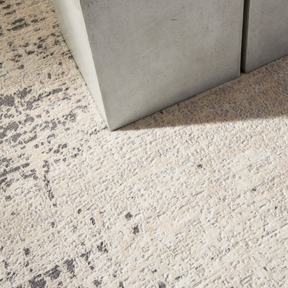 Beige textured rug with dark specks beside grey concrete blocks & industrial modern floor decor.