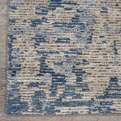 Blue and cream abstract patterned woven area rug with a distressed geometric motif on a light background