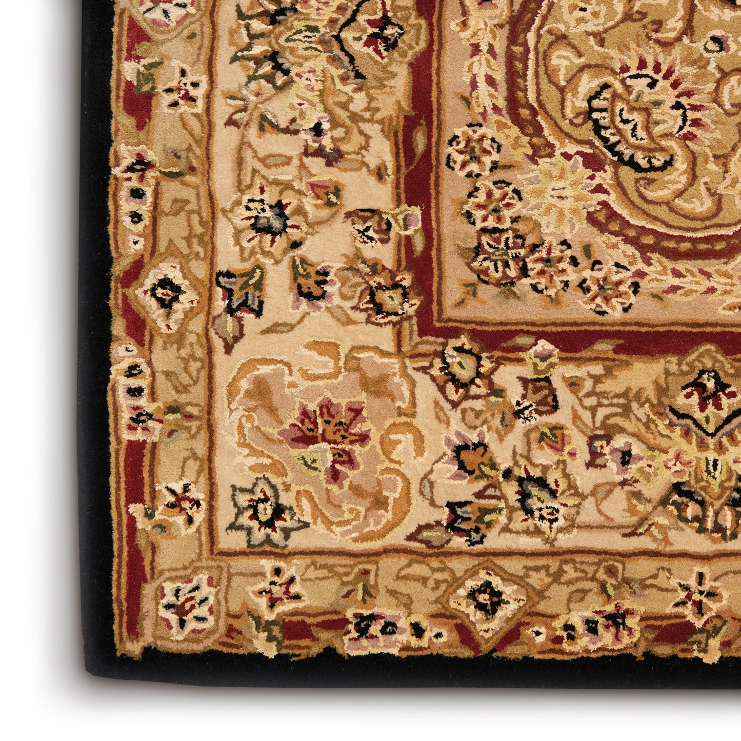 Close-up of a traditional oriental rug with a beige field, red border, and multicolor floral motifs; soft pile and fringe visible.