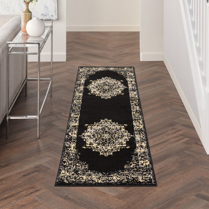 Long black hallway runner rug with cream ornate medallions along the border on dark herringbone flooring beside a metal-framed console.