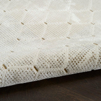 Cream textured rug with square grid weave and small cutouts, edge folded on dark wood floor.