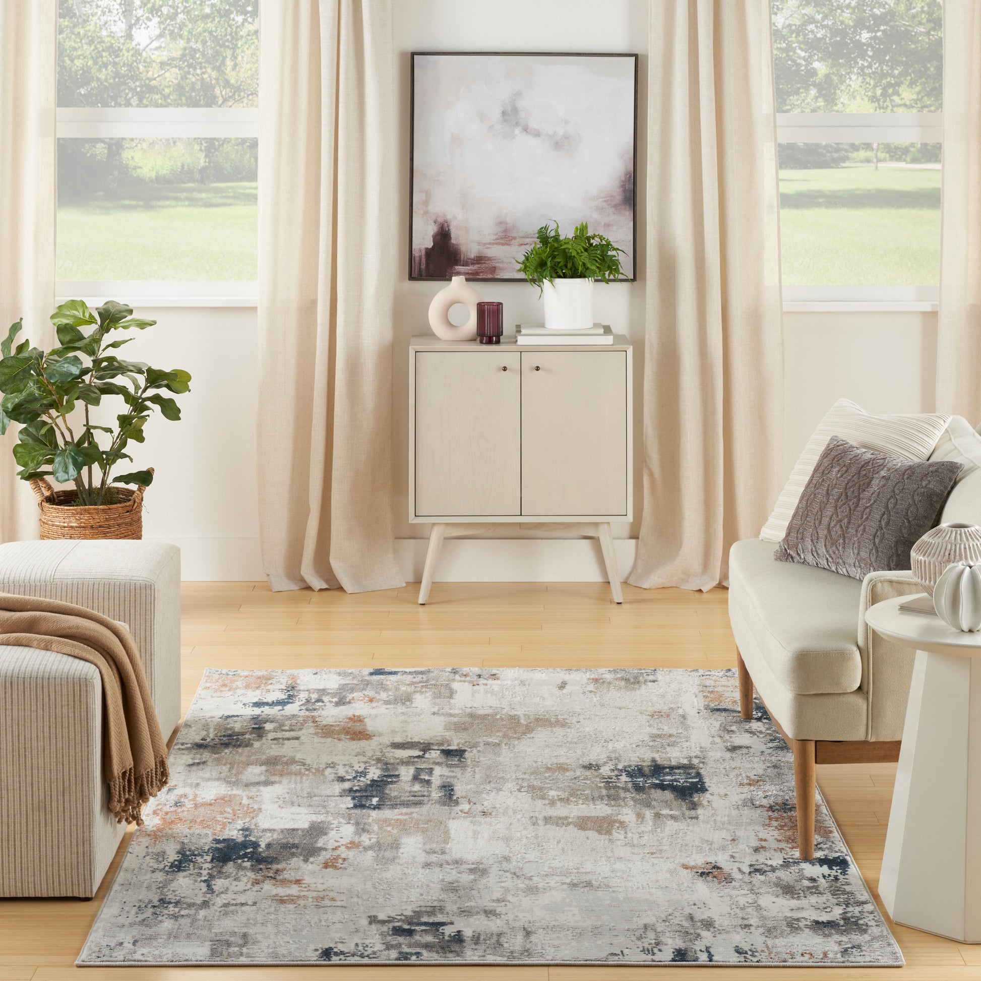 Neutral living room with beige curtains, abstract art, light wood cabinet, plant, cream sofa, and a gray-blue abstract rug.