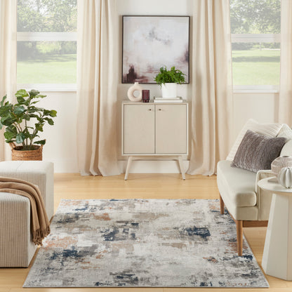 Neutral living room with beige curtains, abstract art, light wood cabinet, plant, cream sofa, and a gray-blue abstract rug.