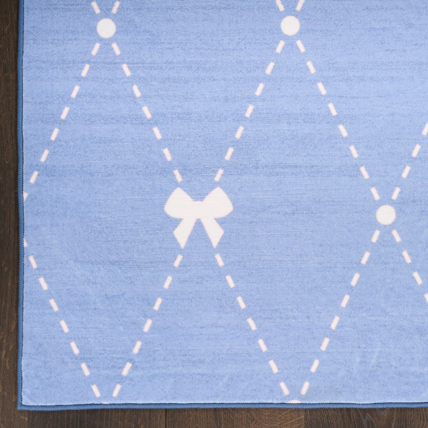 Blue textile with white dashed argyle diamonds and a small white bow accent.
