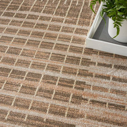 Neutral woven area rug in beige-brown grid pattern beside a white planter with a green plant.