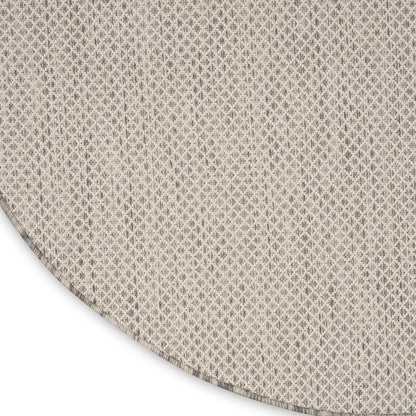 Beige woven fabric with tiny diamond pattern; curved edge hints at a circular rug or throw textile.