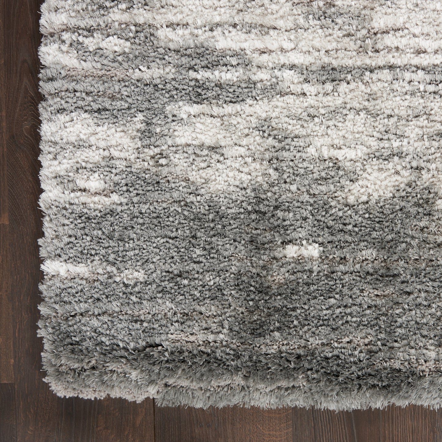 Rectangular grey shag rug with plush high-pile fibers and subtle gradient on dark wood floor.