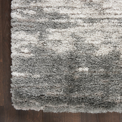 Rectangular grey shag rug with plush high-pile fibers and subtle gradient on dark wood floor.