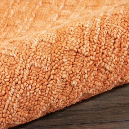 Close-up of bright orange plush shag runner rug with thick looped pile on dark wood floor.