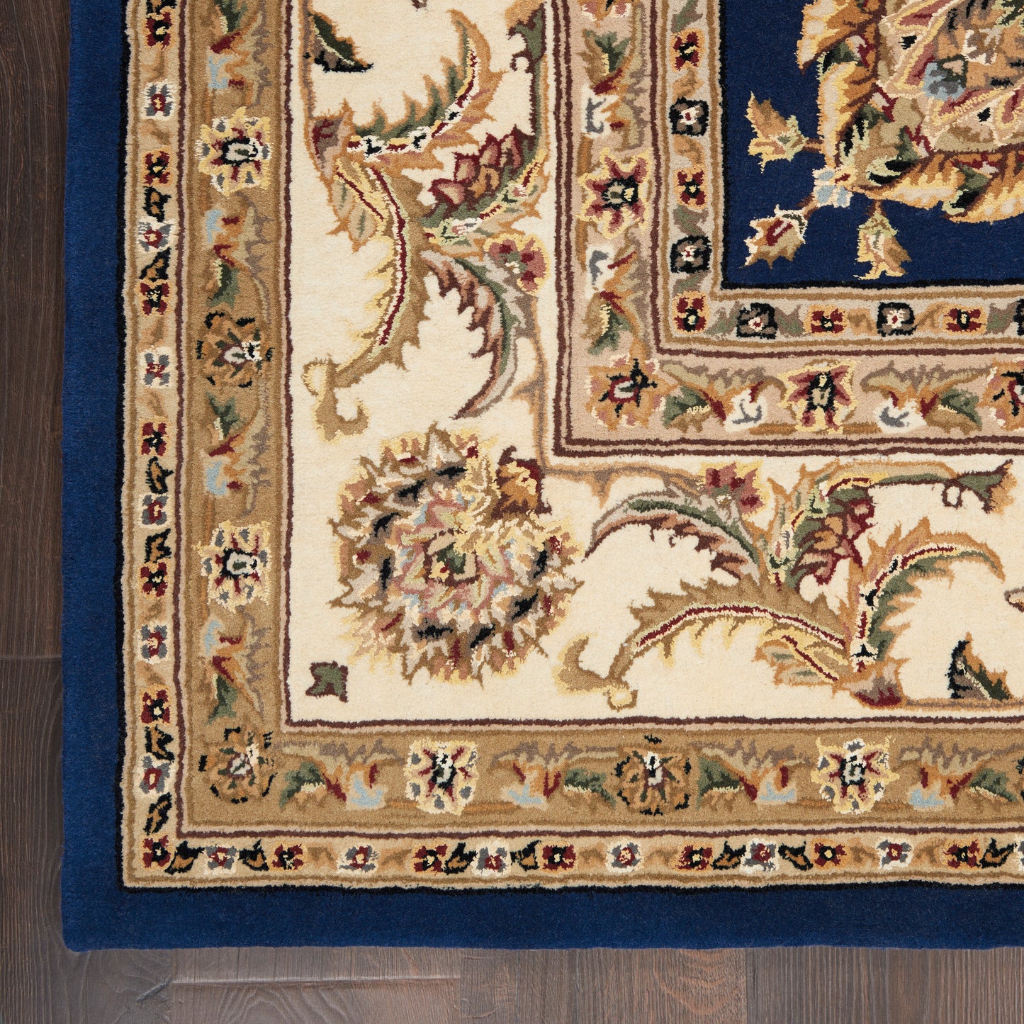 Traditional ornate rug with ivory field, deep blue central panel, and gold floral borders.