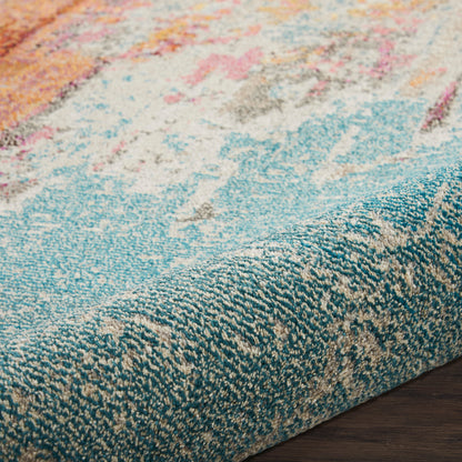 Close-up of a colorful abstract rug with teal edge and peach, pink, blue accents on dark wood floor.