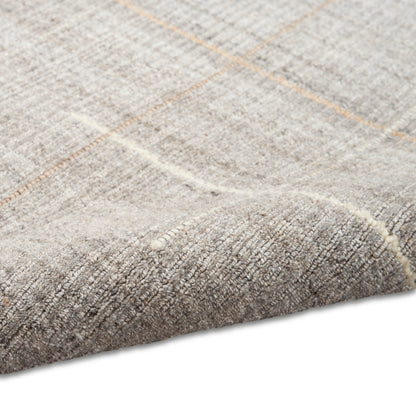 Close-up of a beige-gray woven rug with a soft pile and subtle orange-brown plaid lines.
