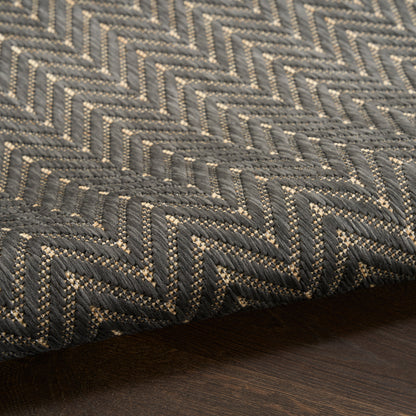 Textured charcoal gray & light gray herringbone woven rug on dark wood floor.