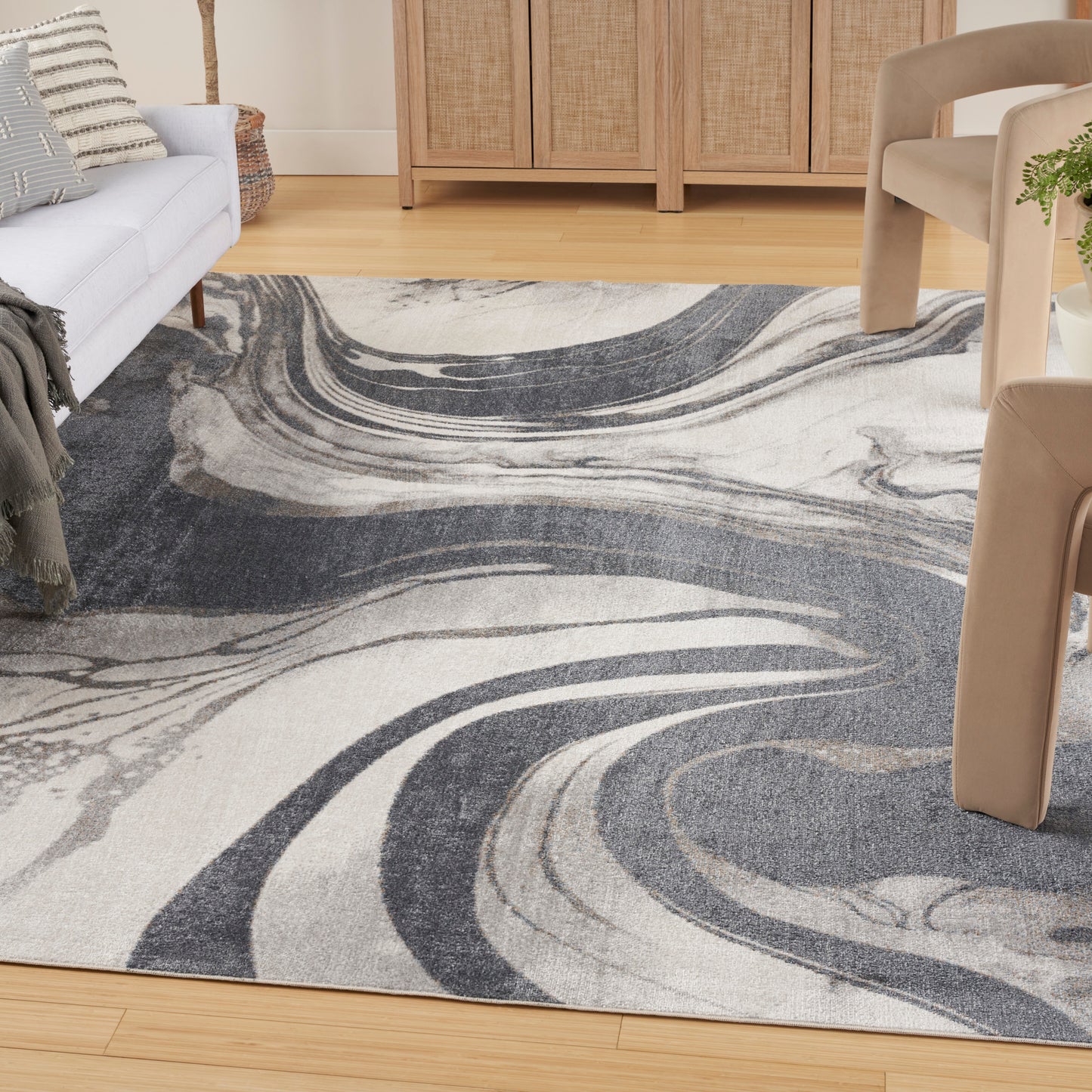 Modern abstract area rug with navy, gray & ivory swirls on a wood floor; living room decor.