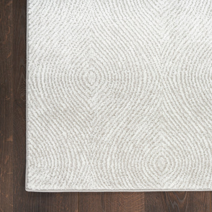 Cream textured area rug with concentric diamond pattern on dark hardwood floor.