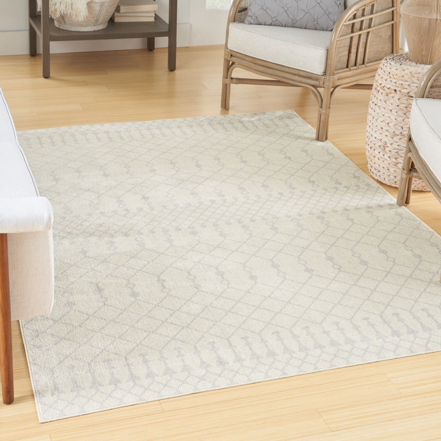 Neutral cream rug with subtle gray lattice pattern on light wood floor, in a wicker-furnished living room.