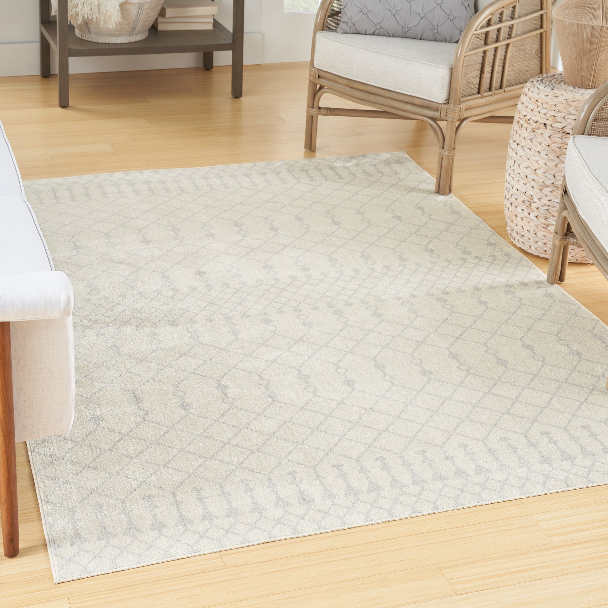 Neutral cream rug with subtle gray lattice pattern on light wood floor, in a wicker-furnished living room.