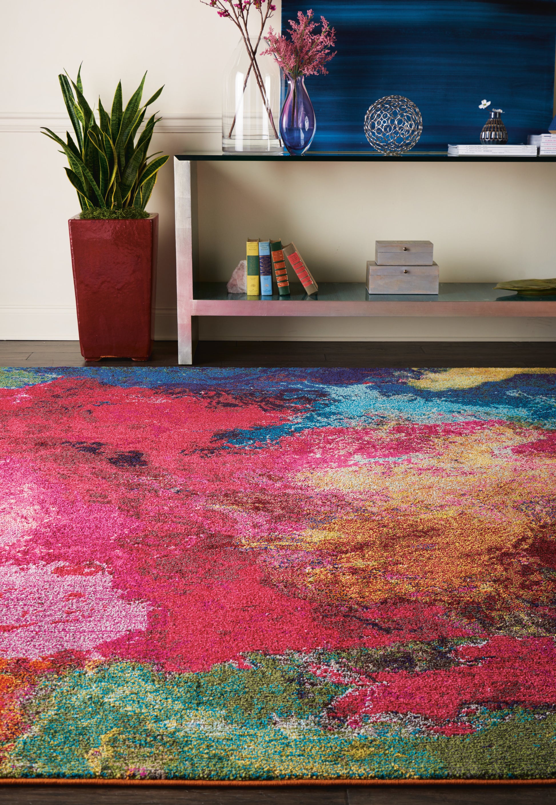 Rectangular, multicolor abstract area rug in pink, red, blue, green & yellow hues for a modern living room.