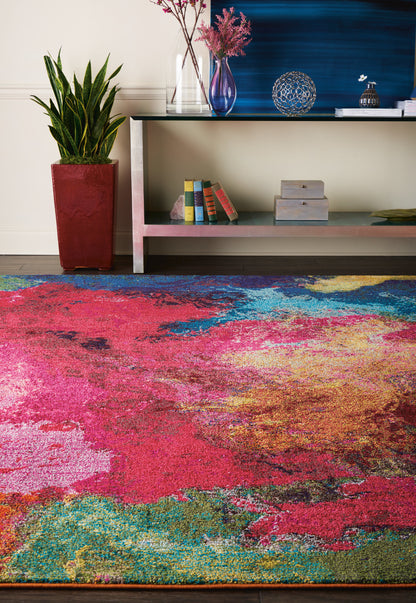 Rectangular, multicolor abstract area rug in pink, red, blue, green & yellow hues for a modern living room.
