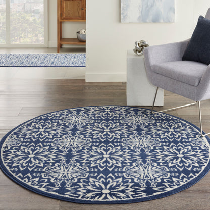 Round blue and white floral-patterned area rug on dark wood floor in a modern living room with a gray armchair.