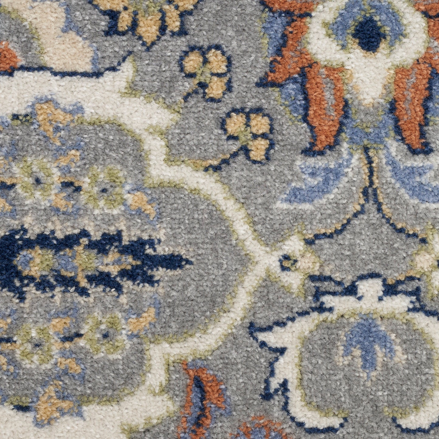 Close-up of a grey ornate area rug with cream, navy, blue and orange floral motifs in a plush tufted pile.
