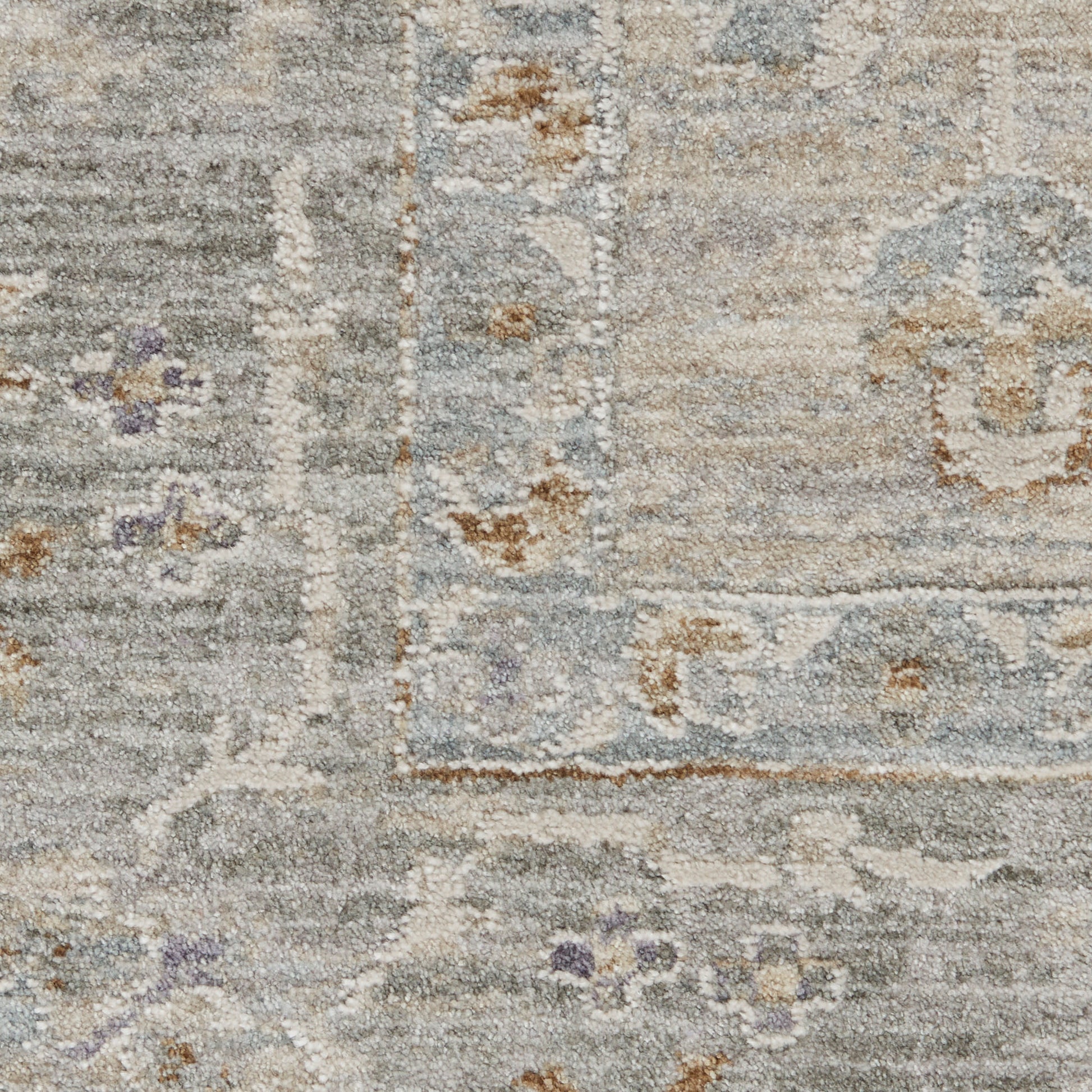 Soft gray-blue rug with ivory border and faded floral pattern in taupe with subtle purple accents.