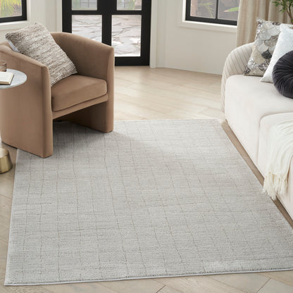 Light gray area rug with a subtle grid pattern in a modern living room; tan armchair and white sofa on light wood floor.