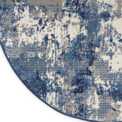 Abstract blue-gray and beige rug with distressed blotch pattern and curved edge.
